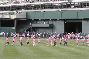 Breast cancer survivors form a ribbon on the field