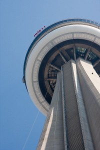 People in orange suits hanging over the edge of the CN tower